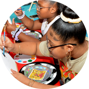 Girls painting on a canvas at a carnival crafted by their event planner for schools