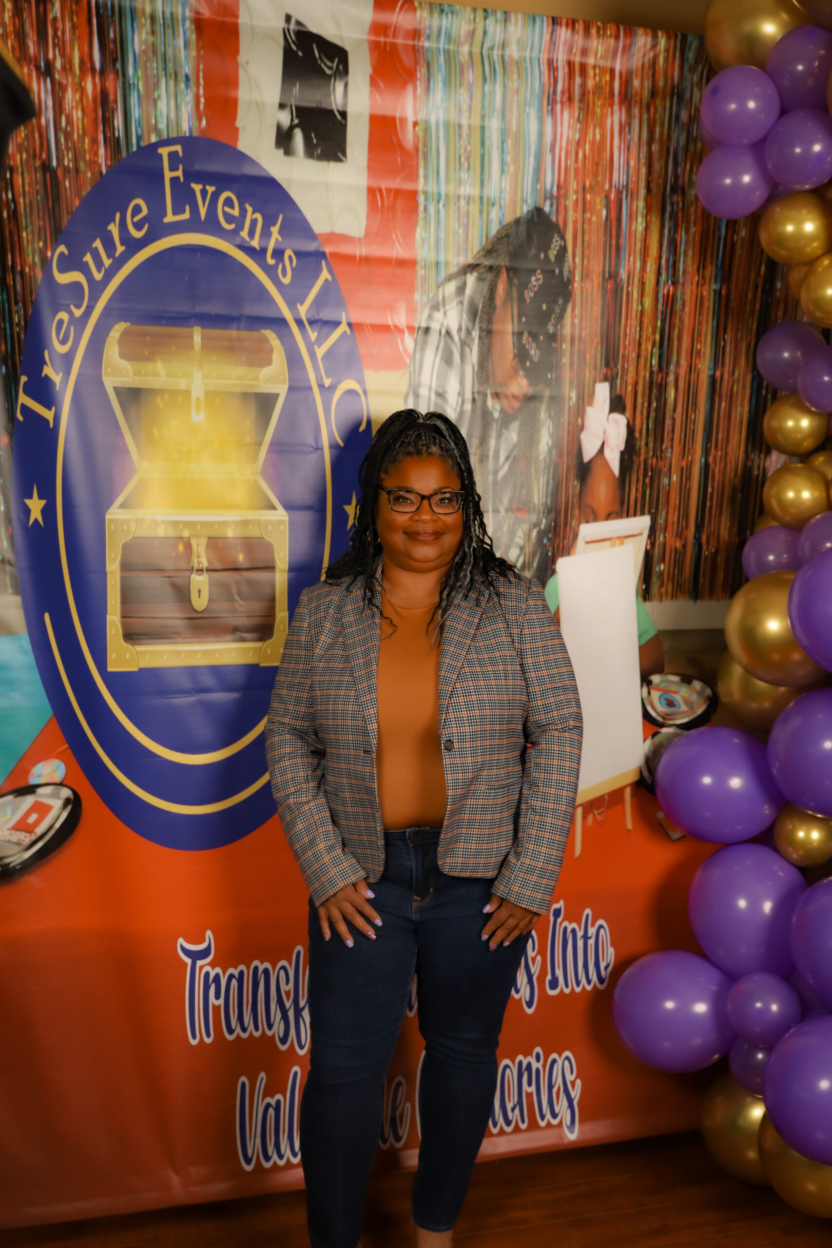 Tesha, head of your Memphis event planners, stands in front of balloon arch and backdrop.