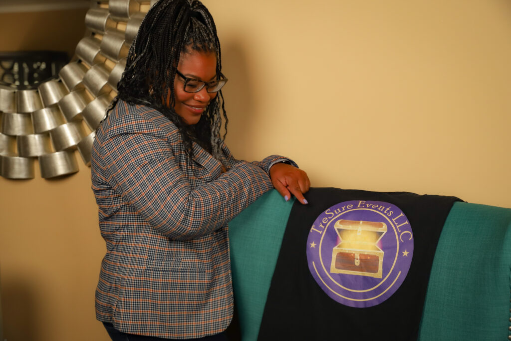 Tesha, head of your Memphis event planners, smiles as she points to a t-shirt with TreSure Events logo.